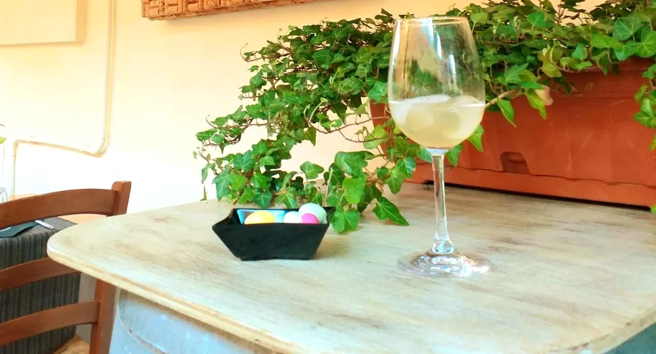 Un calice di vino bianco su una botte, accanto a una fioriera d'edera