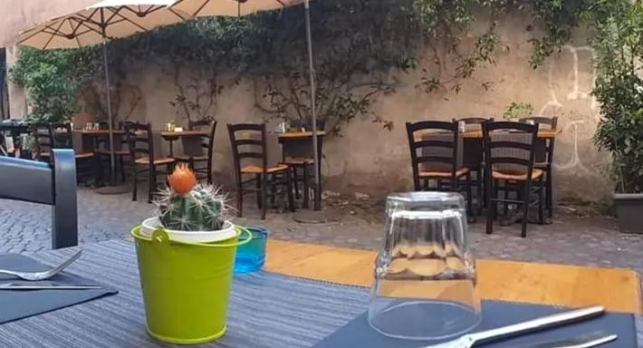 Un tavolo apparecchiato nel vicolo, con un cactus in un secchiello verde